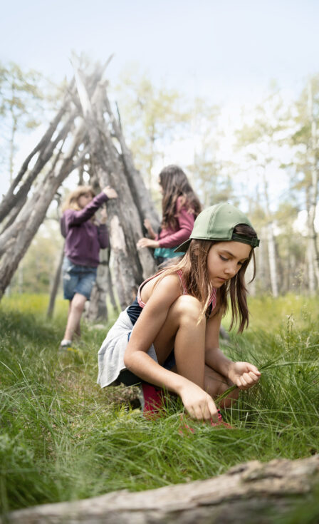 Girl,Friends,Making,Teepee,With,Logs,In,Woods