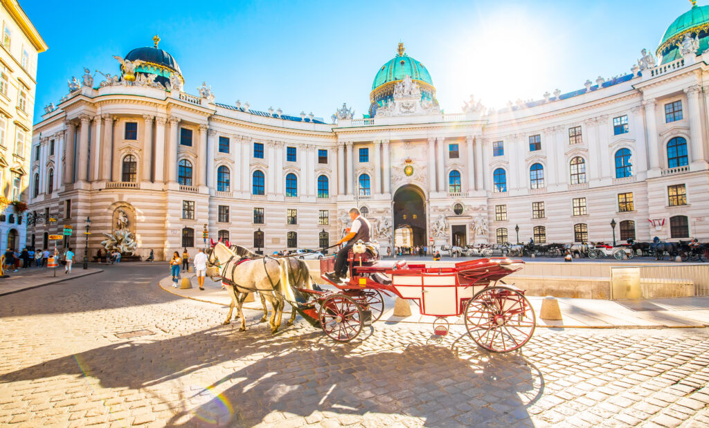 Vienna, Austria - 19 June, 2022: Hofburg Palace and horse carriage on sunny Wien street